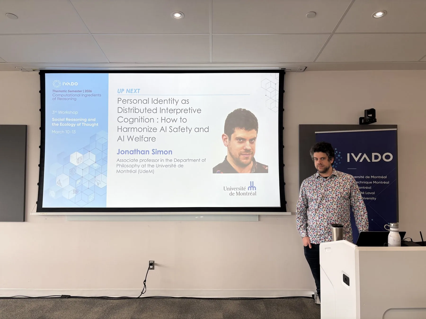 Jonathan Simon beside a slide announcing his talk at IVADO